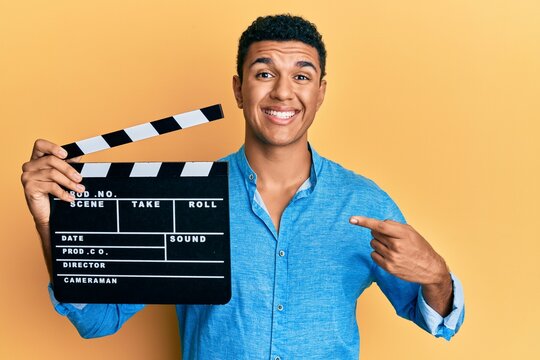 Young arab man holding video film clapboard smiling happy pointing with hand and finger