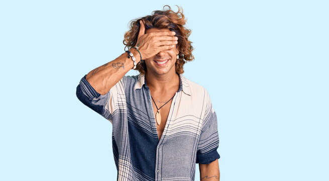Young hispanic man wearing summer style smiling and laughing with hand on face covering eyes for surprise. blind concept.