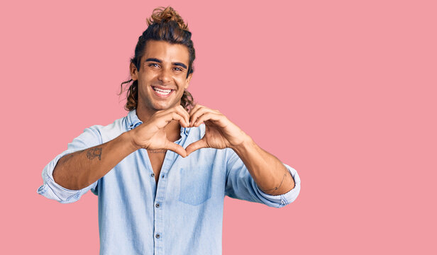 Young hispanic man wearing summer style smiling in love doing heart symbol shape with hands. romantic concept.