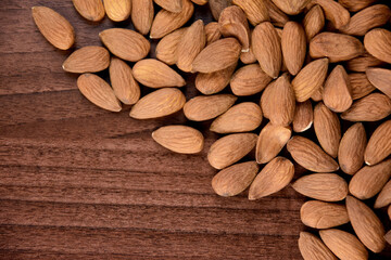 Pile of almonds on the wooden table top view stock images. Almond nuts on a wooden background images. Group of almonds on a brown background stock photo