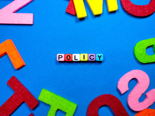 Selective focus.Colorful dice with word POLICY on blue background.Business concept.Shot were noise and film grain.