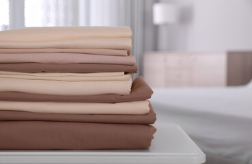 New clean folded bed linens on table indoors. Space for text