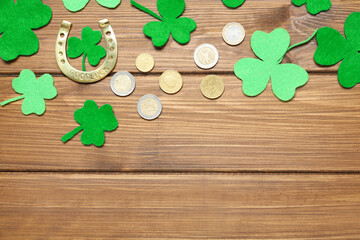 Flat lay composition with clover leaves and horseshoe on wooden table, space for text. St. Patrick's Day celebration