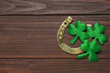 Clover leaves and horseshoe on wooden table, flat lay with space for text. St. Patrick's Day...