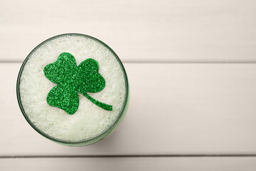 Top view of beer with clover leaf on white wooden table, space for text. St Patrick's Day celebration