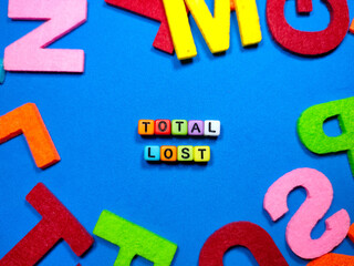 Selective focus.Colorful dice with word TOTAL LOST on blue background.Shot were noise and film grain.