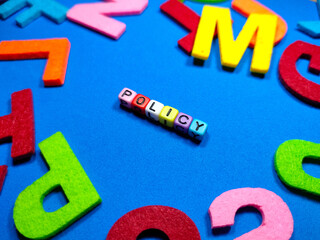 Selective focus.Colorful dice with word POLICY on blue background.Business concept.Shot were noise and film grain.