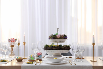 Beautiful Easter table setting with burning candles and floral decor indoors