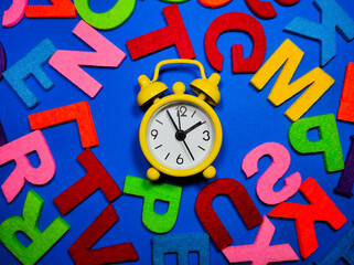 Selective focus.Alarm clock and colorful word on blue background.Shot were noise and film grain.