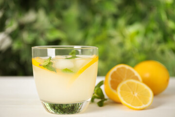 Cool freshly made lemonade in glass on white table