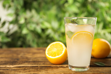 Cool freshly made lemonade in glass on wooden table. Space for text