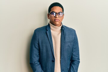 Young handsome hispanic man wearing elegant clothes and glasses relaxed with serious expression on face. simple and natural looking at the camera.