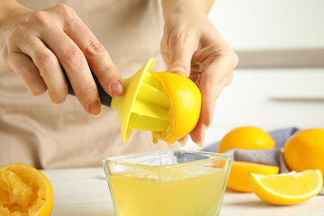 Woman squeezing lemon juice with reamer at table, closeup