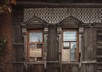 Beautiful decorative platbands on windows of old wooden house. Perm, Russia. Windows close up.