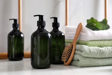 Soap dispensers, brush and towels on countertop in bathroom