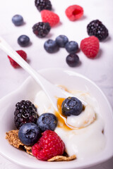 in the heart-shaped bowl ingredients for a healthy breakfast based on: white yogurt, fresh berries and multigrain flakes