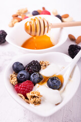 in the heart-shaped bowl ingredients for a healthy breakfast based on: plain yogurt, fresh berries, honey and multigrain flakes
