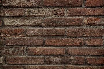 Texture of old dark scary dirty crumbling brick wall of ancient city. Uneven pitted surface of the brickwork of the damp basement with holes and worn. Decayed burnt brickwall background for 3D design