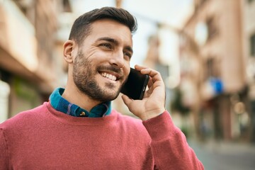 Young hispanic man smiling happy talking on the smartphone at the city.