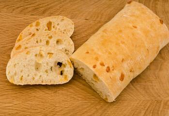 Ciabatta - Italian bread with cheese cut into slices on a wooden board
