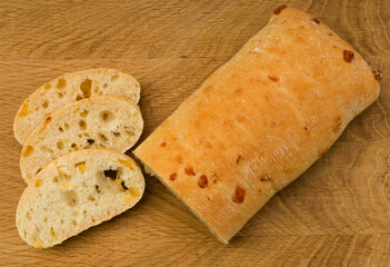 Ciabatta - Italian bread with cheese cut into slices on a wooden board