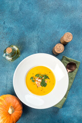 Pumpkin soup in a white plate filmed in decor