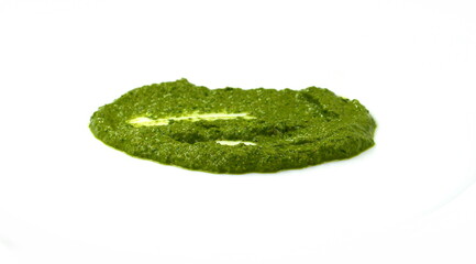 Pesto spread or blob in a bowl isolated on white background. Green italian homemade spilled sauce made of ground basil, garlic, pine seeds, olives and pecorino sardo cheese 