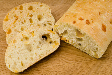 Ciabatta - Italian bread with cheese cut into slices on a wooden board