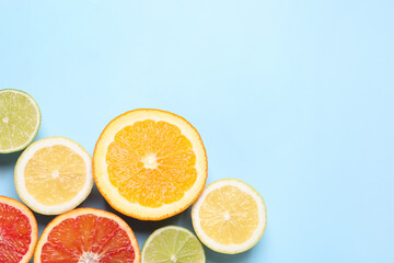 Fresh juicy citrus fruits on light blue background, flat lay. Space for text
