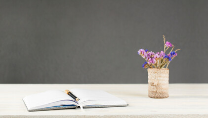 Open notebook and pen. A vase of flowers on the table. Still life.