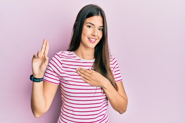 Young brunette woman wearing casual clothes over pink background smiling swearing with hand on...