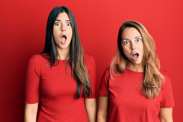 Hispanic family of mother and daughter wearing casual clothes over red background afraid and...