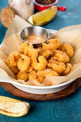 Fried shrimps in a white plate on a blue background