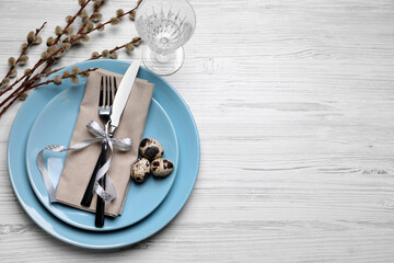 Festive Easter table setting with eggs on white wooden background, flat lay. Space for text