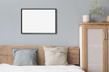 Blank picture frame mockup on gray wall. White bedroom design. View of modern scandinavian style...