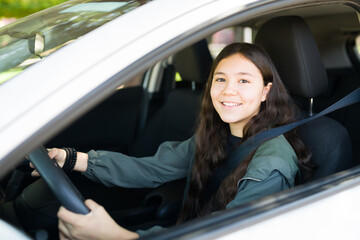 Excited teen girl laughing while driving a new car