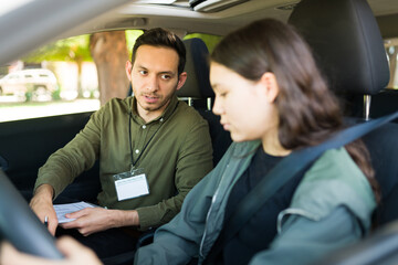 Handsome instructor helping a teen girl to pass her driving test