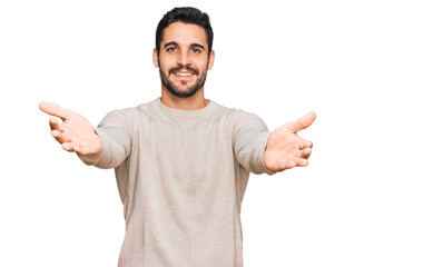 Fototapeta premium Young hispanic man wearing casual clothes looking at the camera smiling with open arms for hug. cheerful expression embracing happiness.