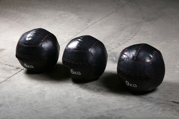 Weighted med ball at gym on the ground, with nobody. Dark background.