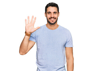 Fototapeta premium Young hispanic man wearing casual clothes showing and pointing up with fingers number five while smiling confident and happy.