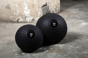 Weighted slam balls at gym on the ground, with nobody. Dark background.