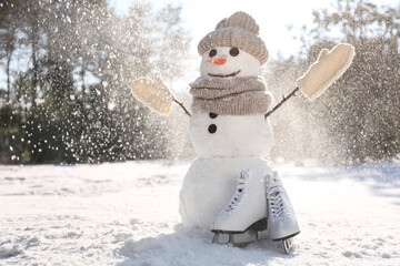 Funny snowman with hat, mittens and scarf in winter forest on sunny day