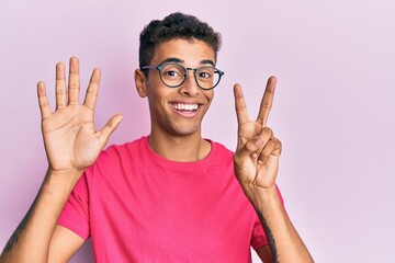 Young handsome african american man wearing glasses over pink background showing and pointing up...