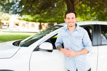 Fototapeta na wymiar Hispanic man smiling and leaning into his white car