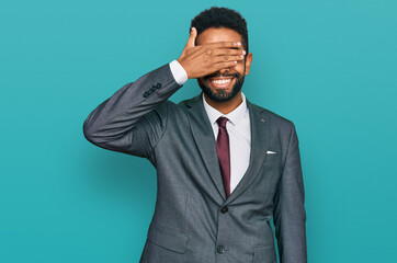Young african american man wearing business clothes smiling and laughing with hand on face covering eyes for surprise. blind concept.