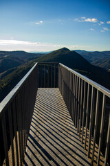 Obraz premium Iron bridge over the precipice in the mountains with panoramic views of the mountain range and the sky beyond the horizon
