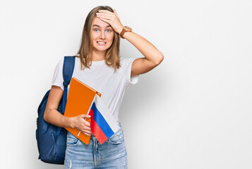 Beautiful young blonde woman exchange student holding russian flag stressed and frustrated with hand on head, surprised and angry face