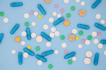 A lot of colorful medical pills, capsules on blue background with copy space. Background from multi-colored medical capsules, tablets. Medical layout. World Pharmacist's Day