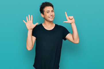 Young handsome man wearing casual black t shirt showing and pointing up with fingers number seven while smiling confident and happy.