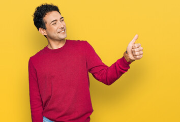 Young handsome man wearing casual clothes looking proud, smiling doing thumbs up gesture to the side